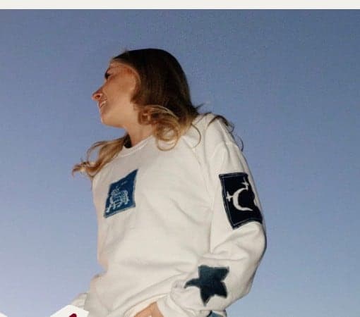 A cream crewneck with denim patchwork and a star on the sleeve